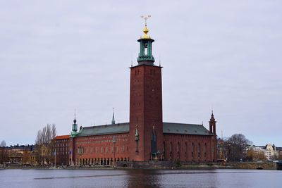 Lighthouse by river against buildings in city