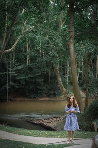 Full length portrait of a girl standing on water in forest