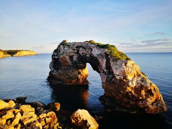 Rock formation in sea against sky