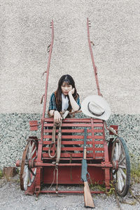 Woman sitting on bicycle against wall