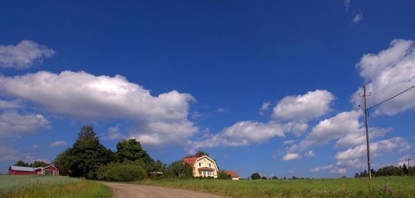 Houses and trees on field against sky