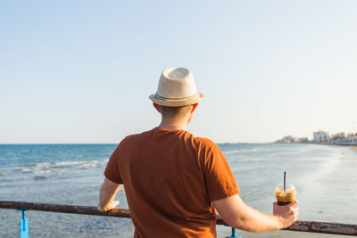 Rear view of man at beach against sky