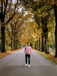 Full length rear view of man walking on road in forest