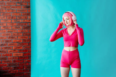 Portrait of young woman standing against wall