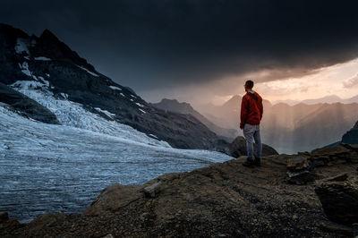 Rear view of man standing on rock against sky