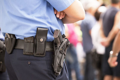 Midsection of police officer with handgun and handcuffs