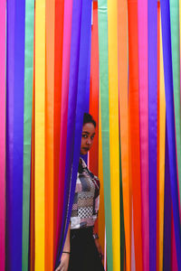 Full length of woman standing against multi colored wall