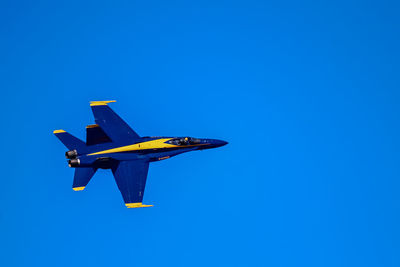 Low angle view of airplane flying against clear blue sky