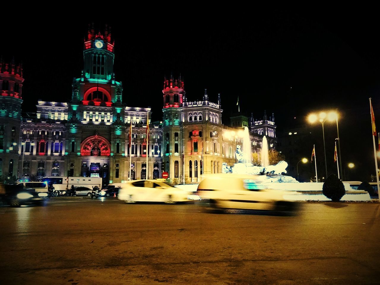 building exterior, architecture, built structure, night, illuminated, city, street, transportation, car, street light, city street, land vehicle, road, city life, mode of transport, incidental people, clear sky, building, travel destinations, outdoors