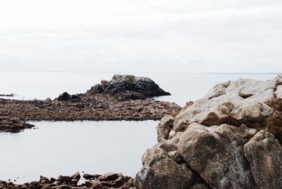 Rock formations on beach against sky