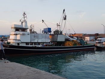 Boats moored at harbor against sky