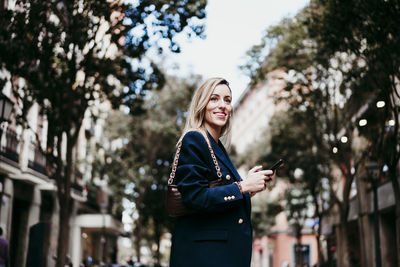 Young woman using mobile phone while standing on camera