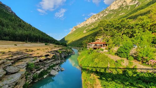 Scenic view of tree by mountain against sky, river reflection of sky and trees