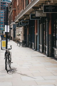 Bicycle on footpath by street against buildings in city