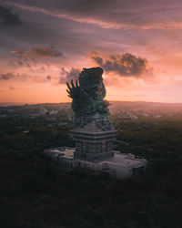 Statue in city against sky during sunset