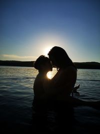 Couple on shore against sky during sunset