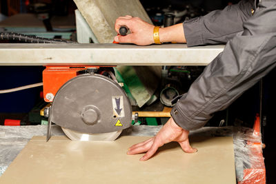 The master cuts a tile on an industrial machine with a diamond blade.