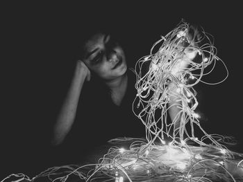 Close-up of young woman holding light over black background