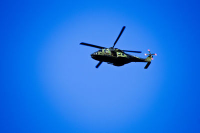 Low angle view of military helicopter flying in clear blue sky