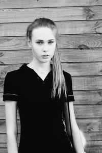 Portrait of young woman standing against wall