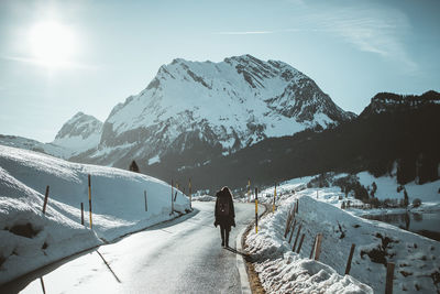 Person walking on snow covered mountain against sky