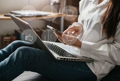Midsection of woman using mobile phone while sitting at home