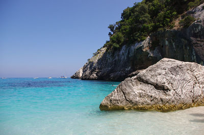 Rock formation in sea against clear blue sky