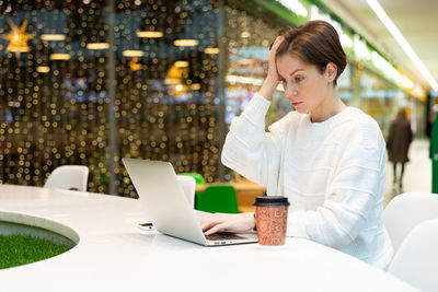 Frustrated woman using laptop in shopping mall