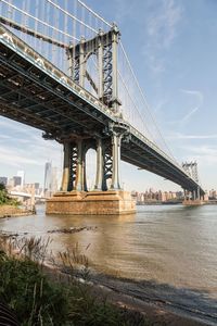 Low angle view of manhattan bridge over east river against sky