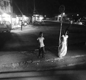 Rear view of girl walking on road at night