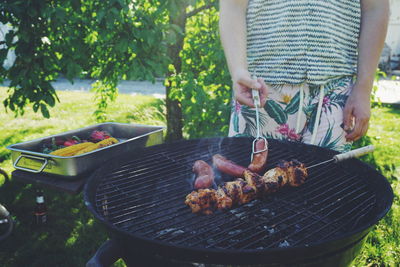 Man preparing food on barbecue grill in yard