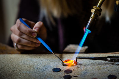 Close-up of person working with flaming torch on table