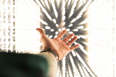 Hand of young reaching towards illuminated lighting equipment