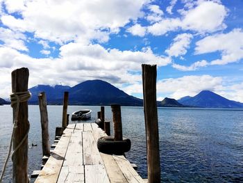 Wooden posts on pier over sea against sky