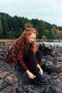 Full length of woman sitting on rock