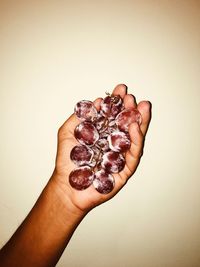 Midsection of person holding ice cream against wall