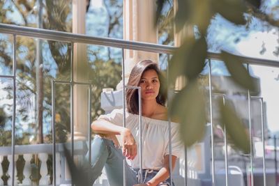 Portrait of young woman looking through railing outdoors