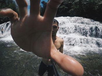 Midsection of shirtless man standing in water