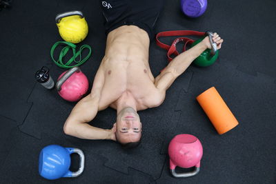 Directly above portrait of man lying by equipment on floor in gym