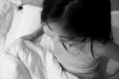 High angle view of girl sitting on bed at home