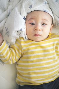 High anlge portrait of cute baby lying on bed at home