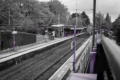 Railroad station platform by trees against sky