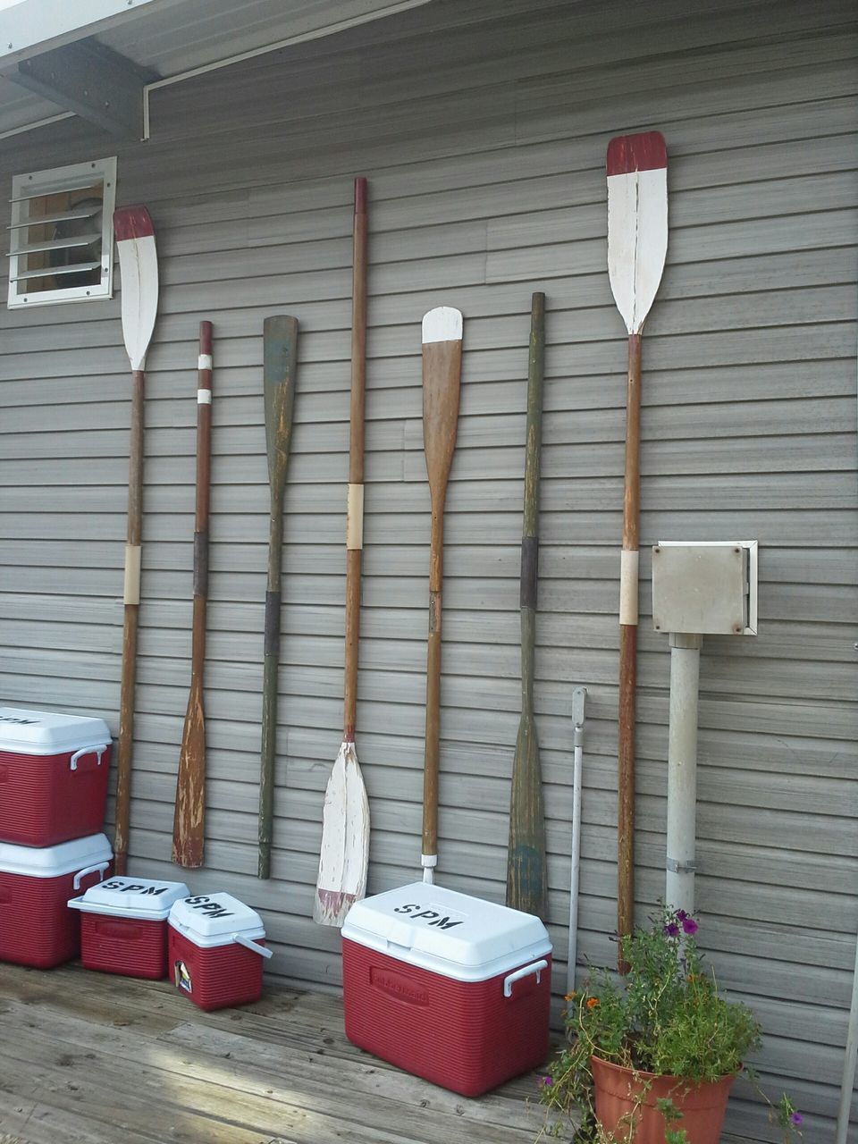 wall - building feature, hanging, built structure, red, architecture, building exterior, chair, no people, day, in a row, wall, variation, arrangement, absence, potted plant, large group of objects, side by side, empty, table, outdoors