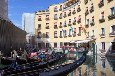 Gondola boats moored in canal by buildings