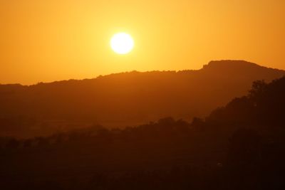 Scenic view of silhouette landscape against orange sky