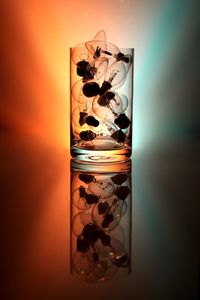 Electric bulb in drinking glass against colored background