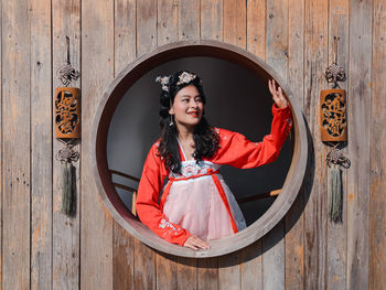 Asian woman tourist in red hanfu ancient chinese traditional ethnic costume looking out of window