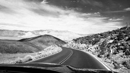 Road by mountains against sky seen through car windshield