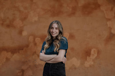 Portrait of smiling young woman standing against wall