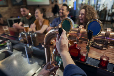 Cropped hands of bartender serving beer at bar